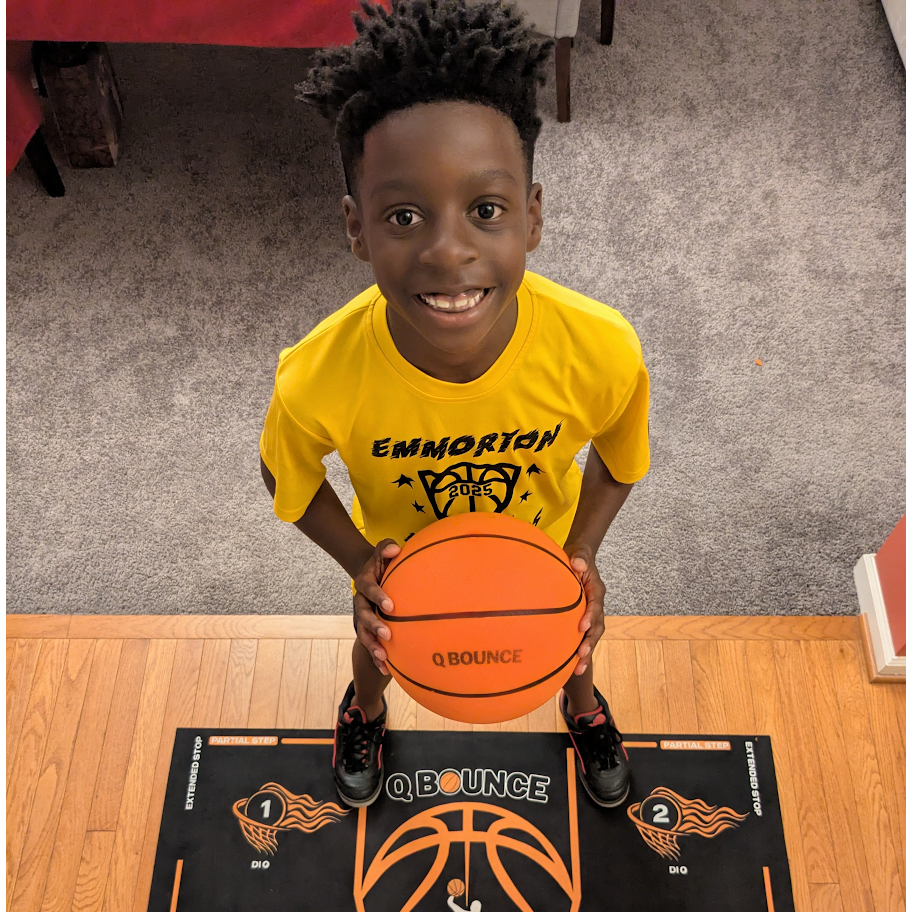Young player holding a QBounce silent basketball on a training mat at home